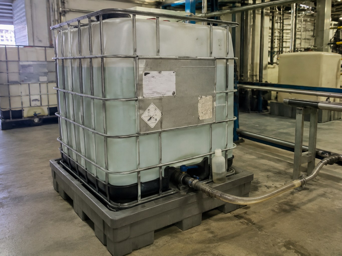Translucent acrylamide solution IBC connected to a transfer line in a polymer production bay