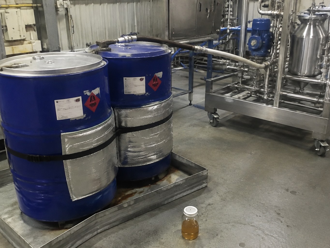 Alkenyl succinic anhydride drums beside a stainless paper-sizing preparation skid.