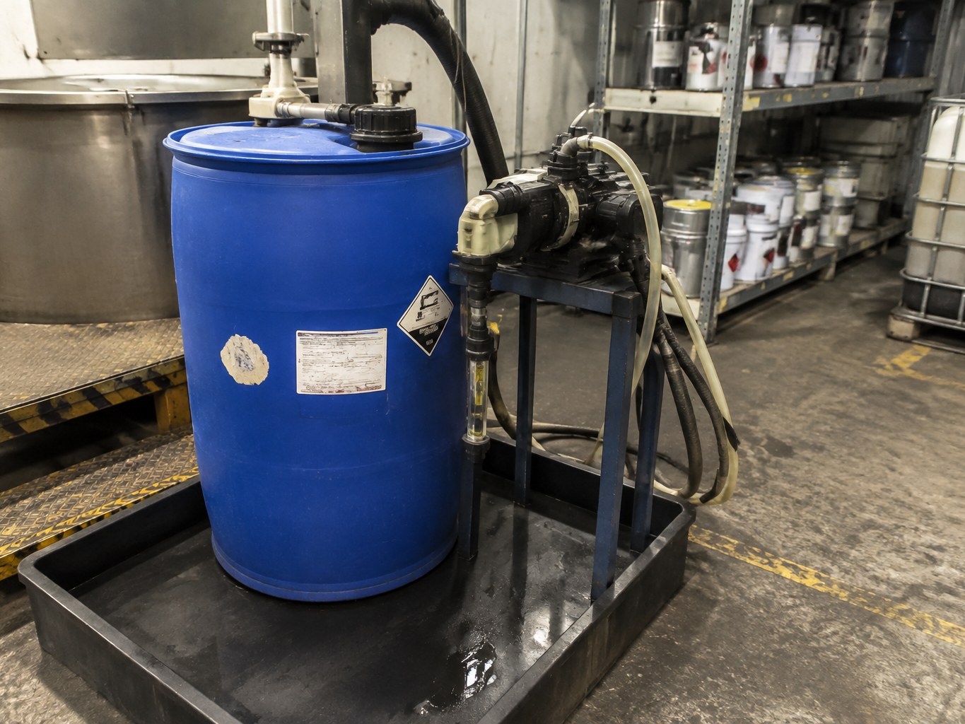 Pumped blue drum of butyldiethanolamine in a contained chemical blending area.