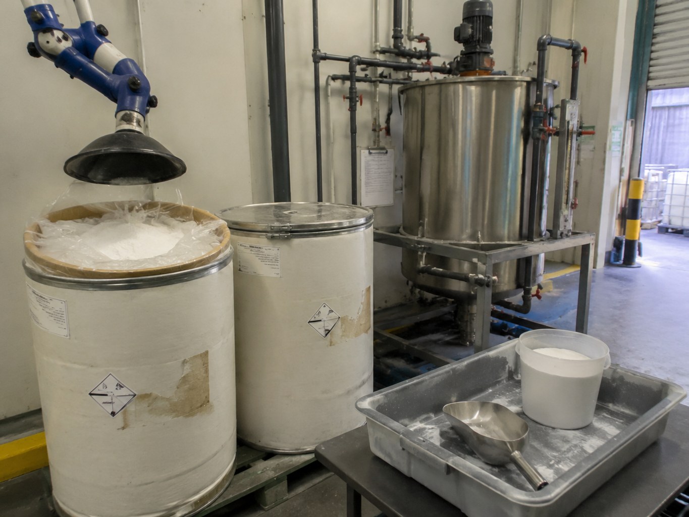 Open fibre drum of white carbohydrazide powder beside a boiler-water make-down tank