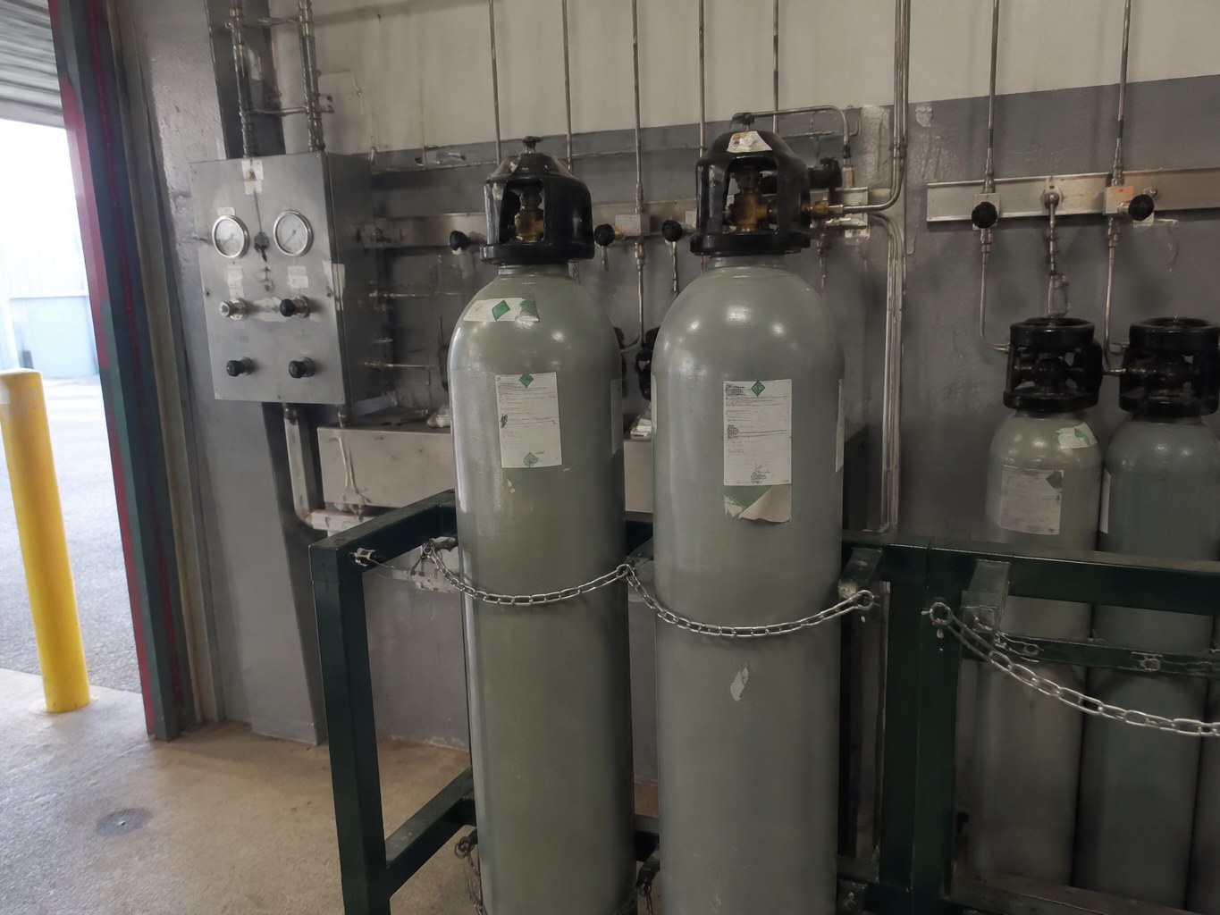 Secured carbon tetrafluoride cylinders connected to an electronics specialty-gas manifold.