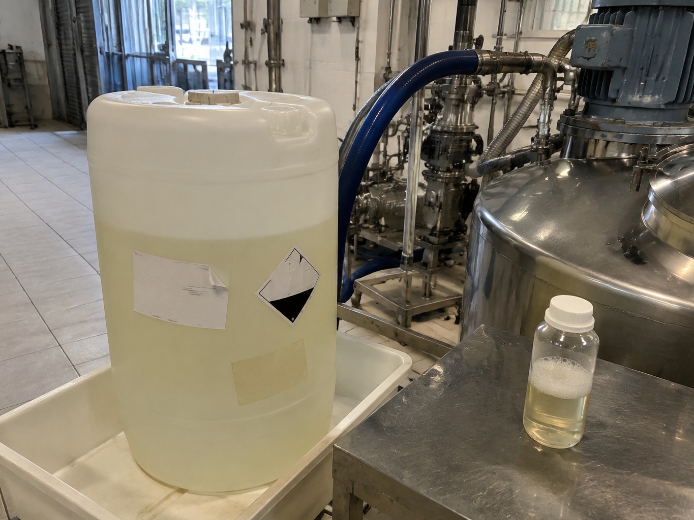 Pale cetrimonium chloride solution in an HDPE jerrican beside a surfactant mixer.