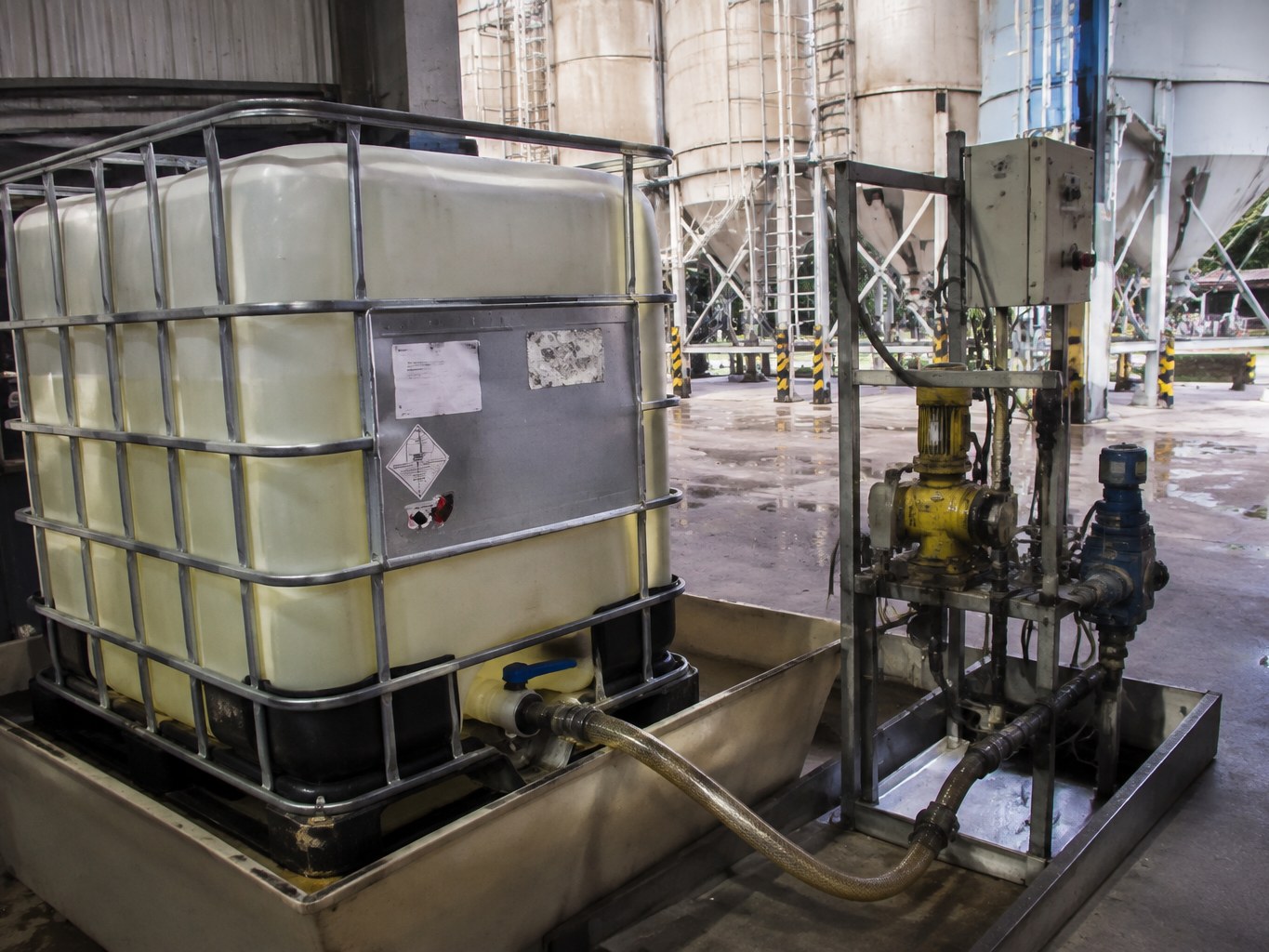 Pale diethanol isopropanolamine in an IBC connected to cement-additive dosing equipment.
