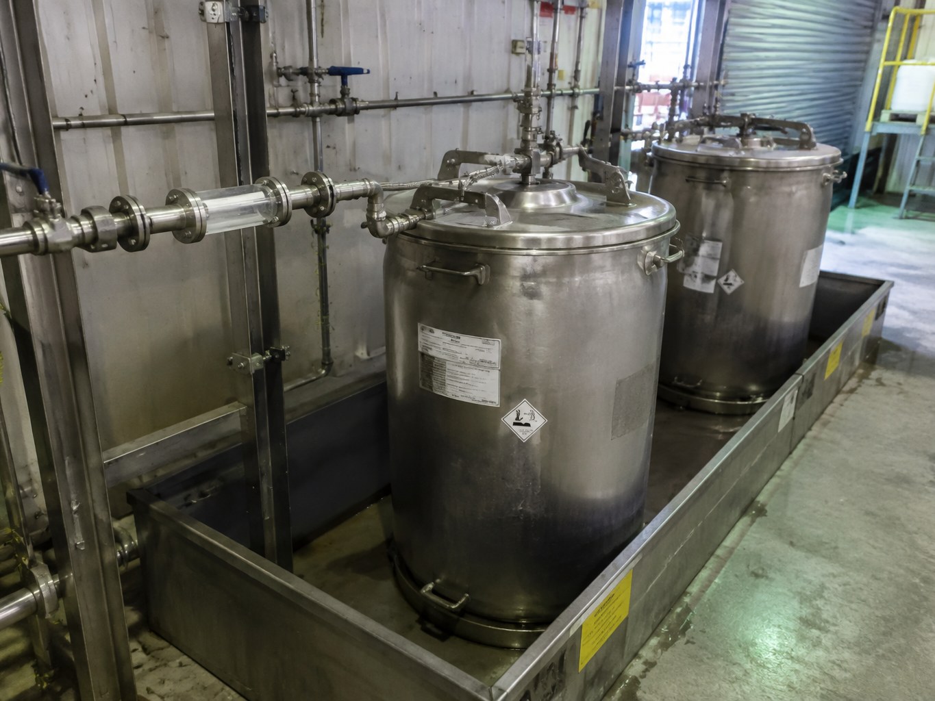 Stainless diethyl sulfate containers connected to a closed transfer line in a synthesis bay