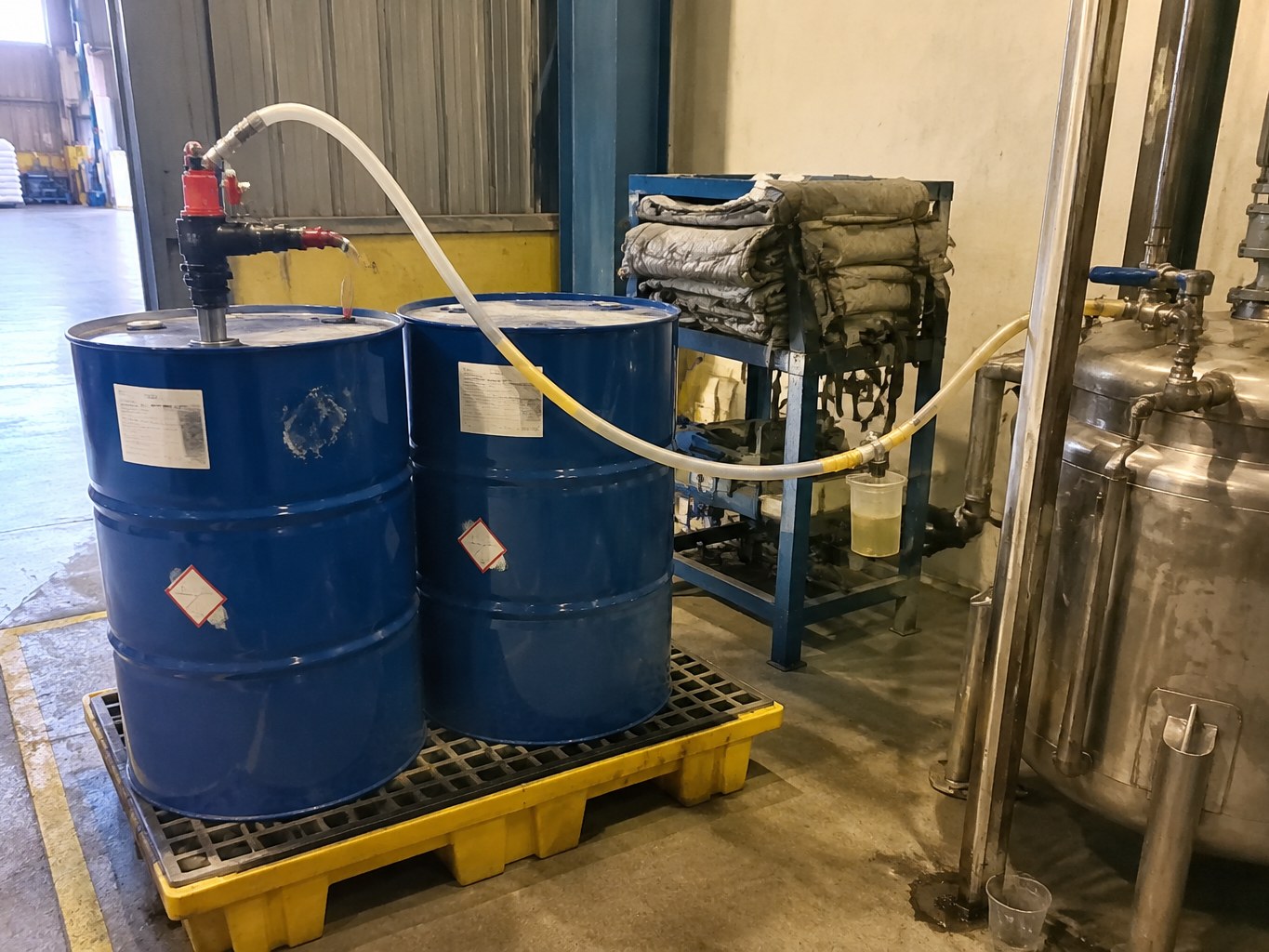 Blue drums of diisopropanolamine connected to dosing equipment in a blending area