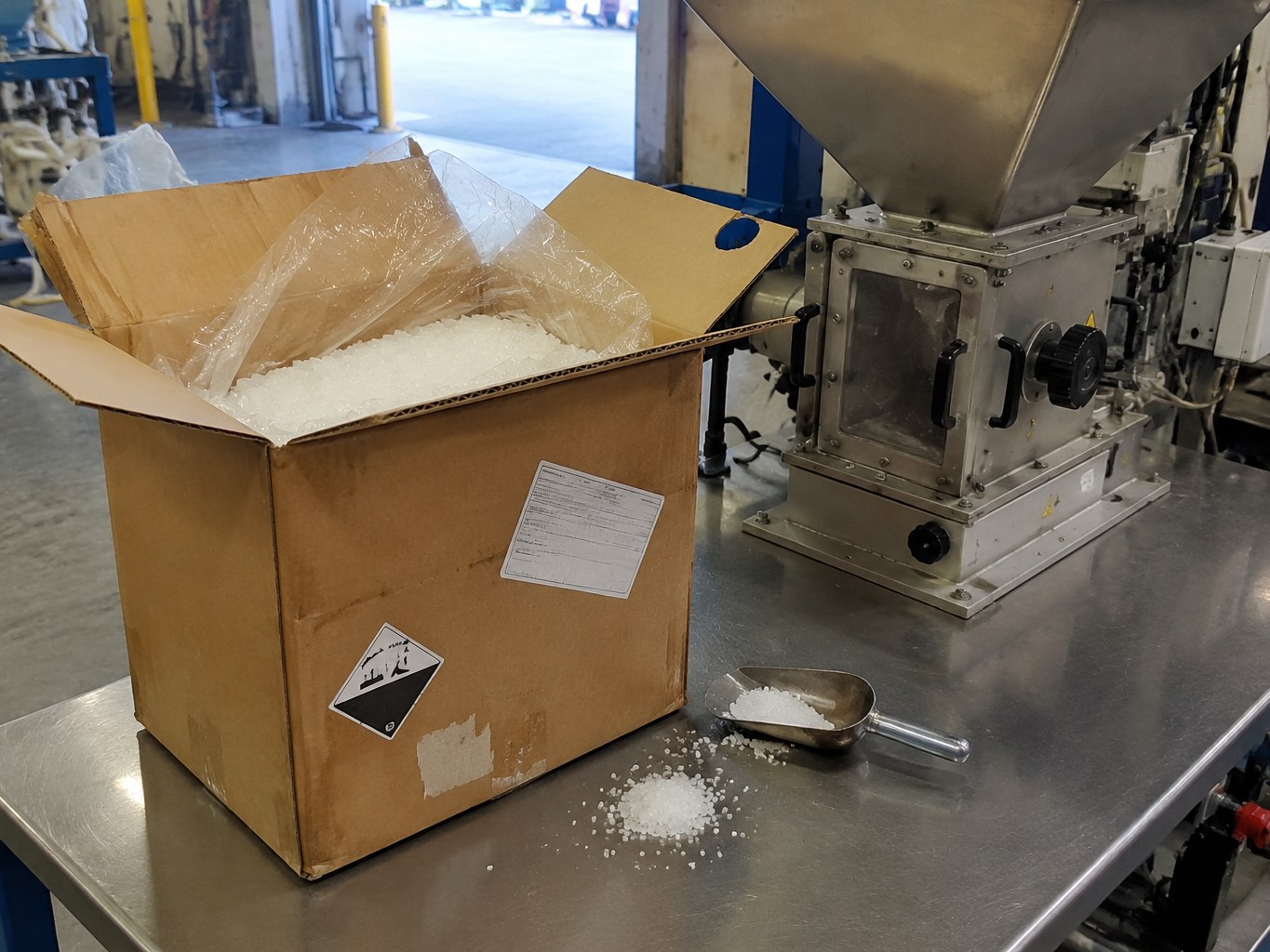 White dilauryl thiodipropionate powder in an open lined carton beside a feeder.