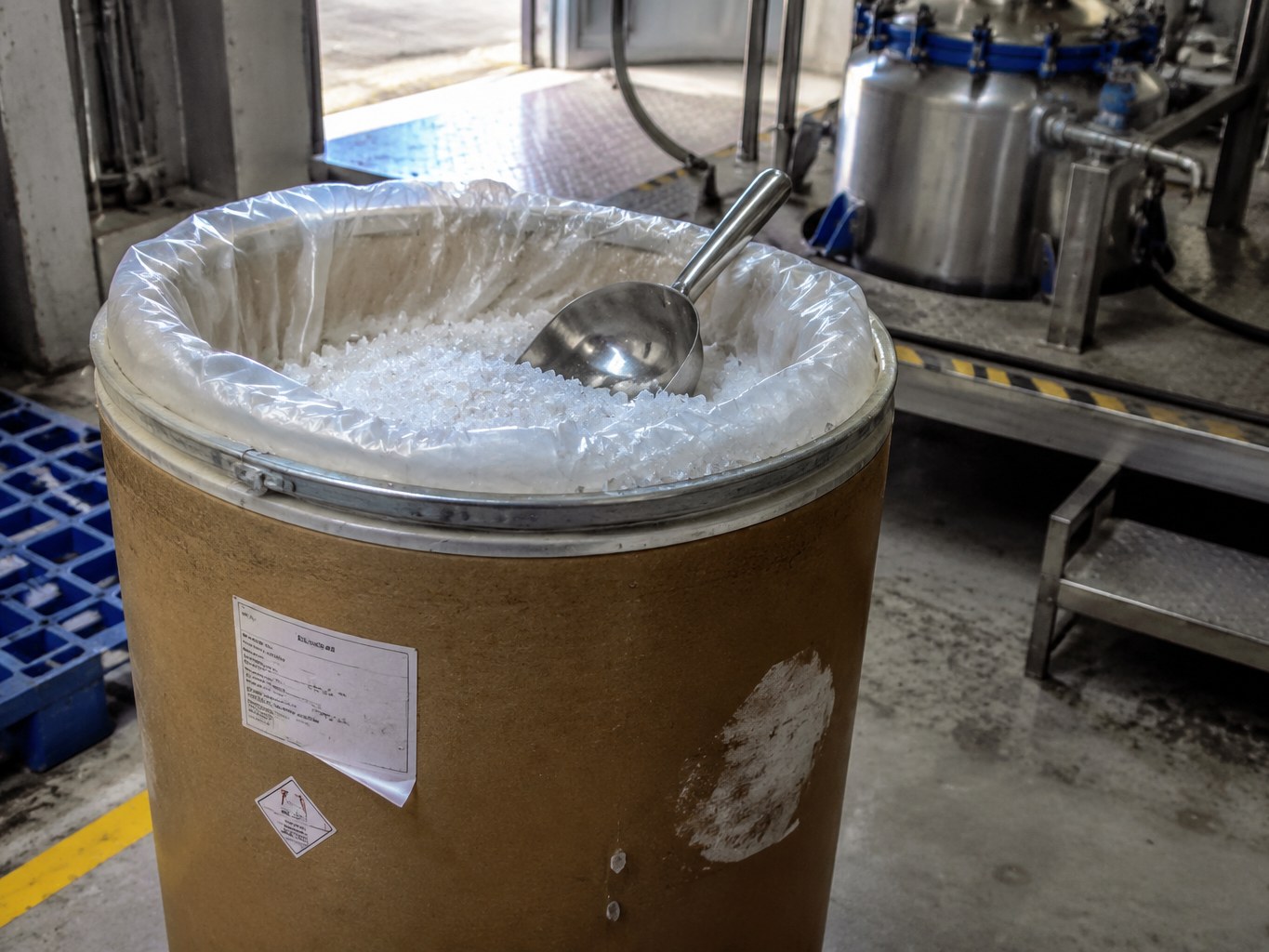 White dimethyl oxalate crystals in a lined fibre drum inside a synthesis plant.