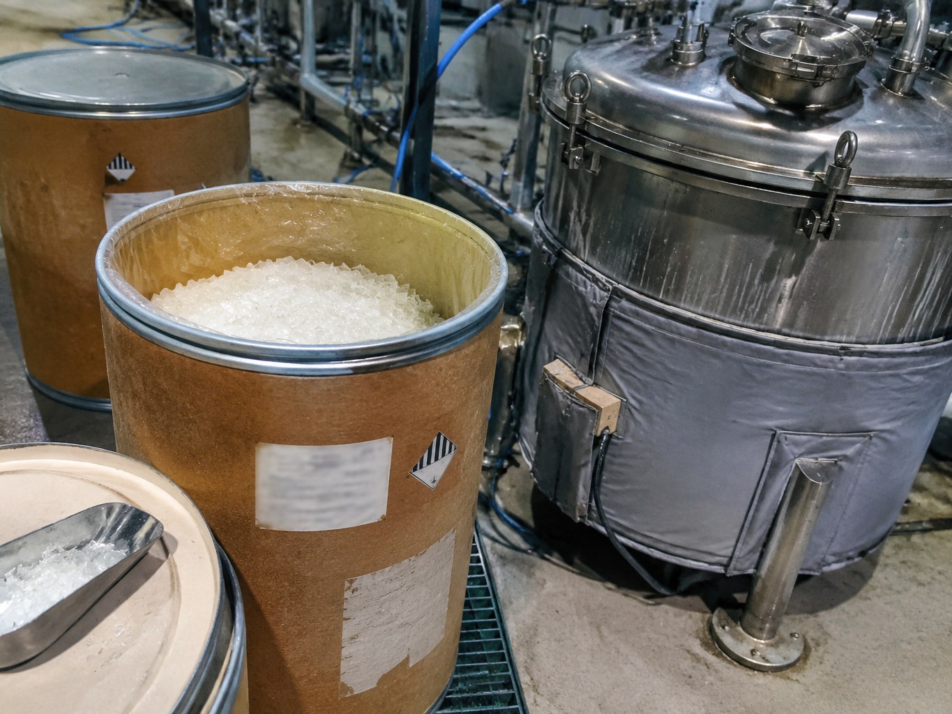 Open fibre drum of diphenyl oxide crystals beside a jacketed process vessel