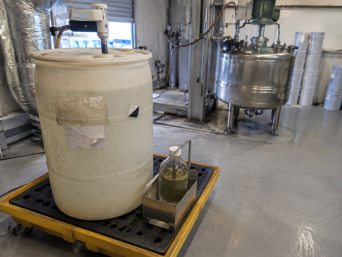 HDPE drum of dipropylene triamine with a sample bottle near a resin kettle.