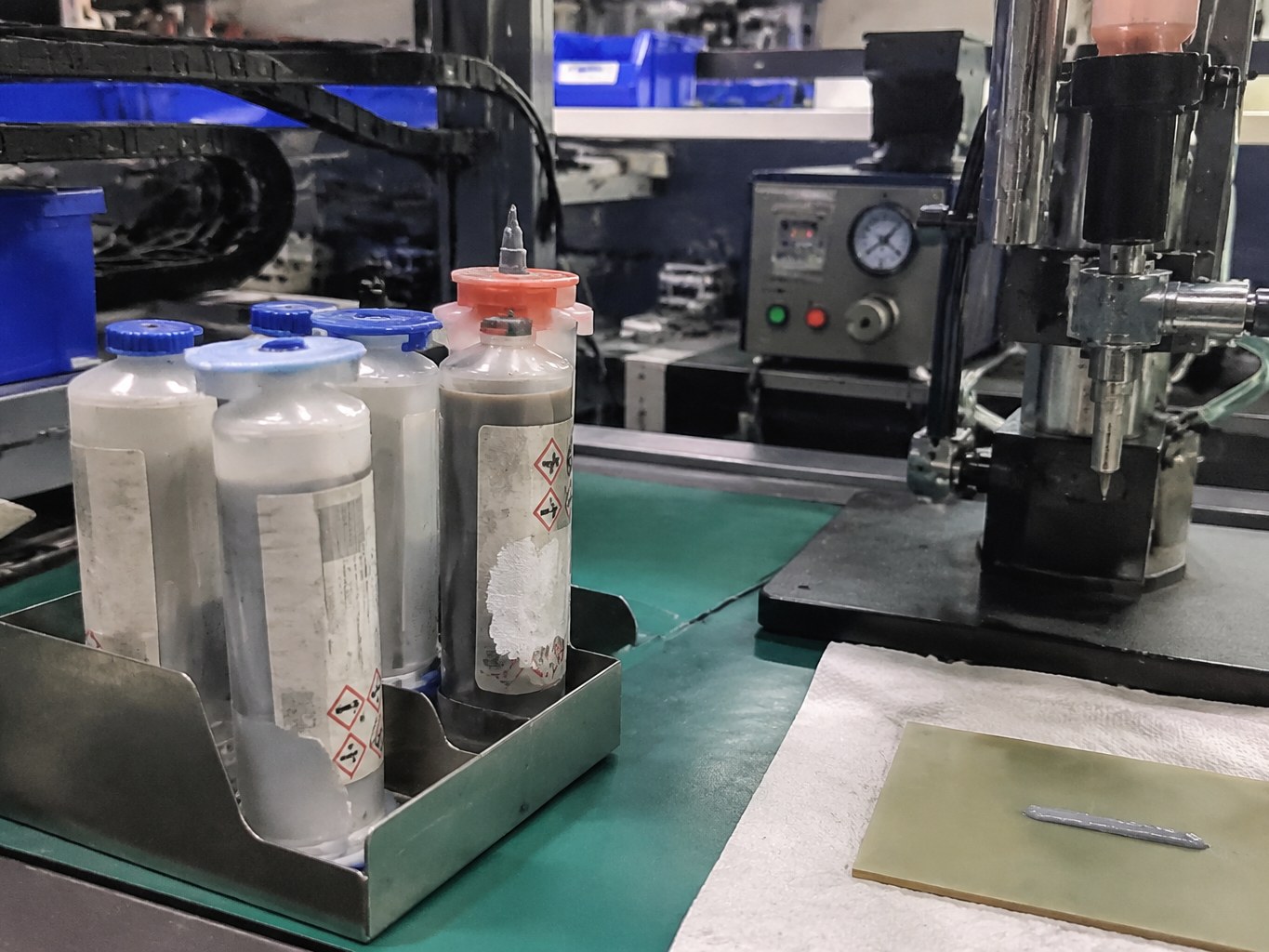 Dispensing bottles of silver conductive adhesive on an electronics assembly bench.