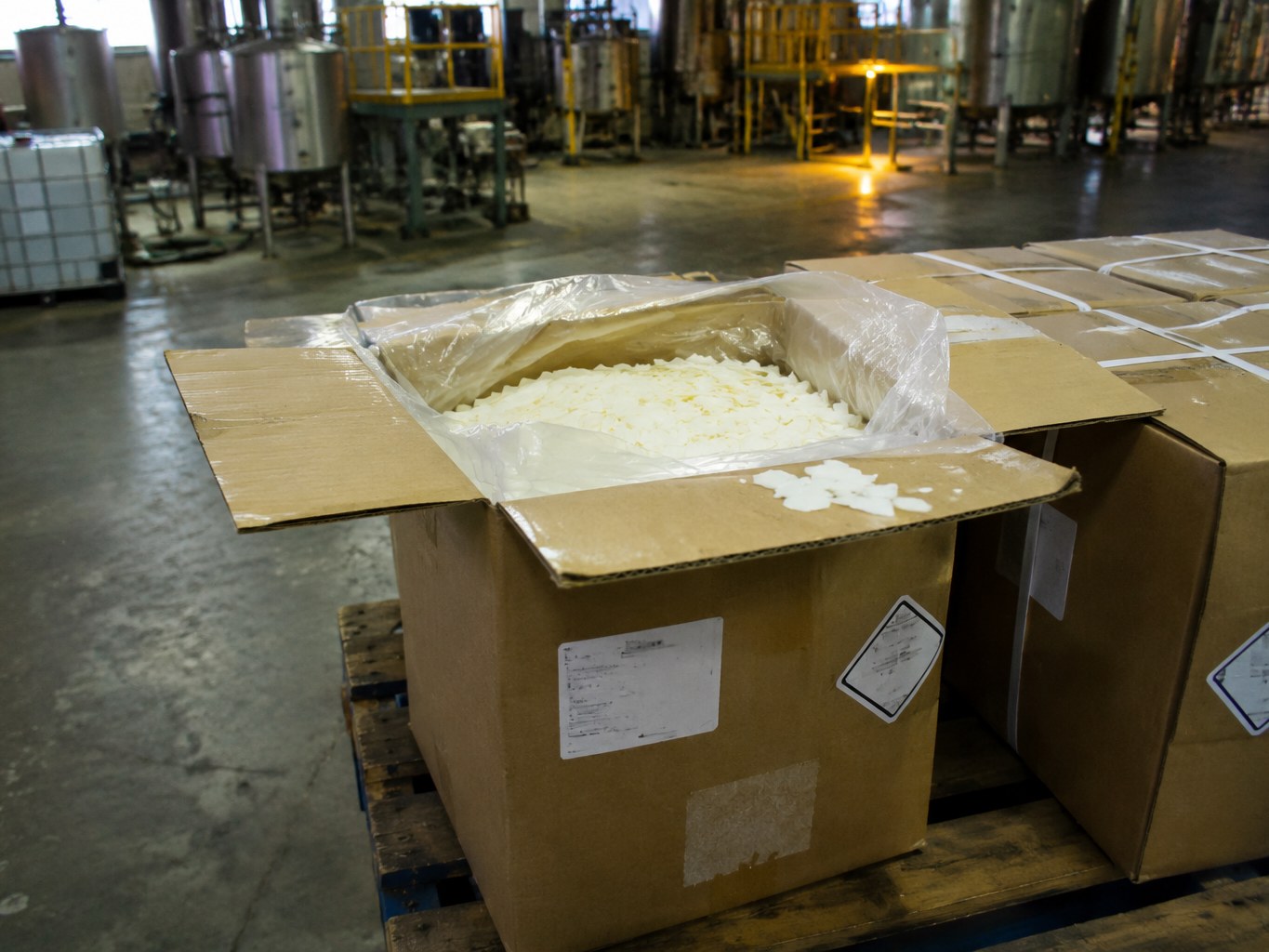 Lined carton of pale erucic acid flakes on a pallet in an oleochemical plant.
