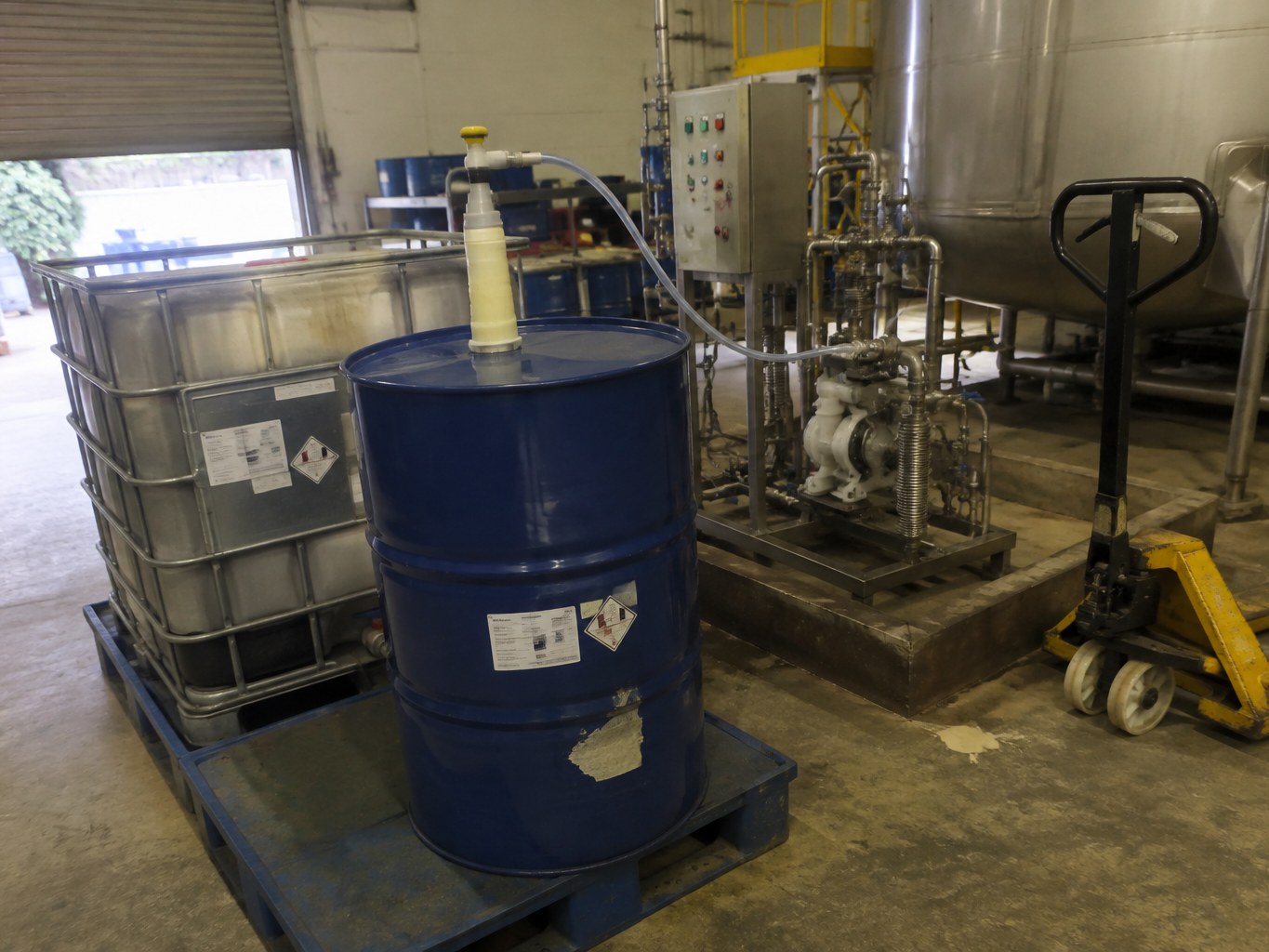 Blue ethylethanolamine drum beside an IBC and dosing skid in a blending bay