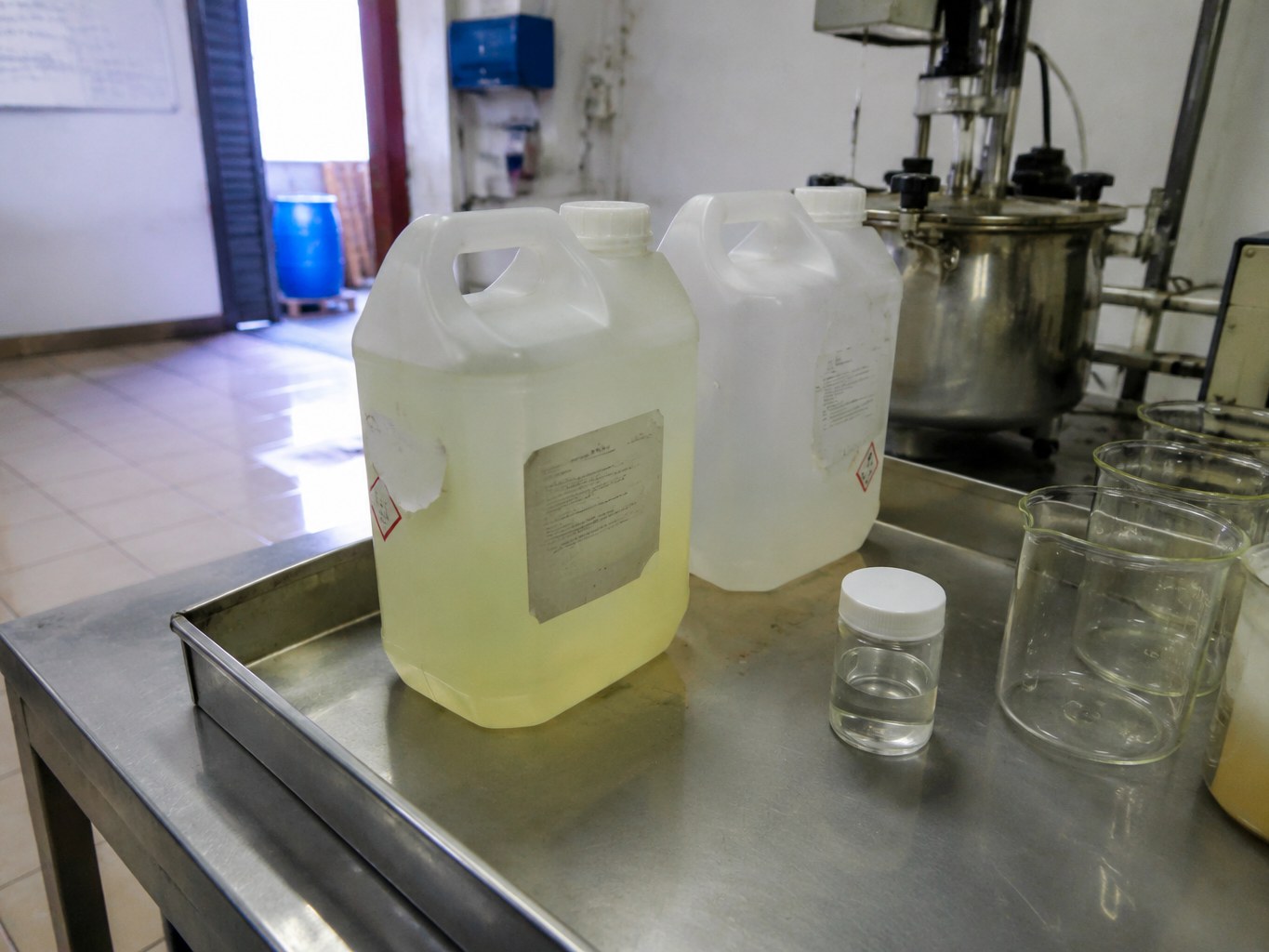 Pale isoamyl laurate liquid in HDPE jerricans on a formulation bench.