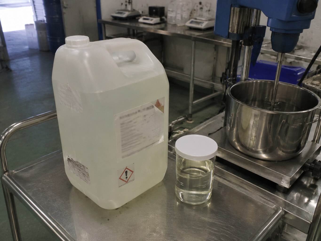 Translucent isononyl isononanoate jerrycan and clear sample beside a cosmetics mixer.