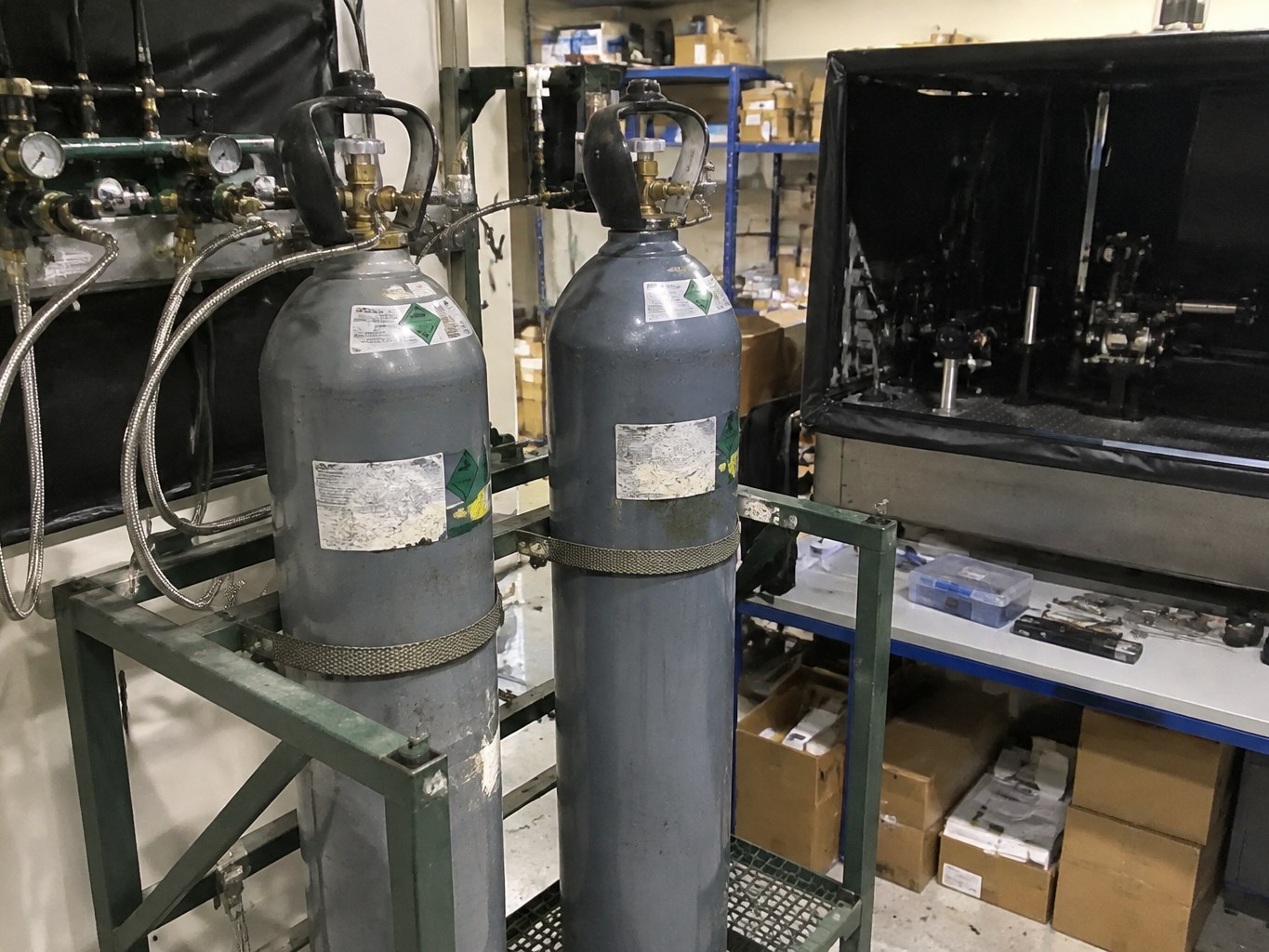 Krypton cylinders connected to gas lines beside laser and lighting equipment.