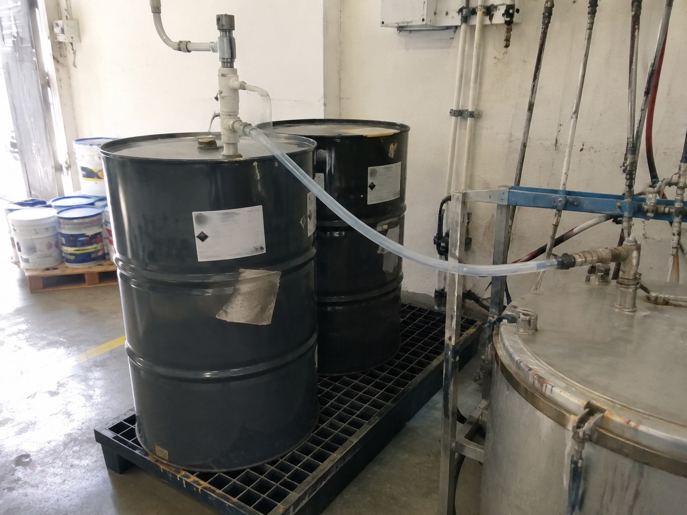Black drums of methyl propyl ketone connected to a solvent transfer tank
