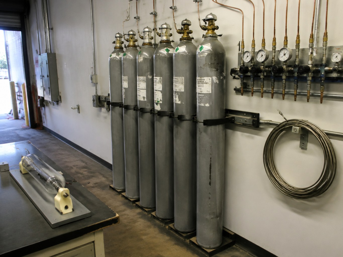 Neon gas cylinders connected to a regulator manifold in a laser workshop.