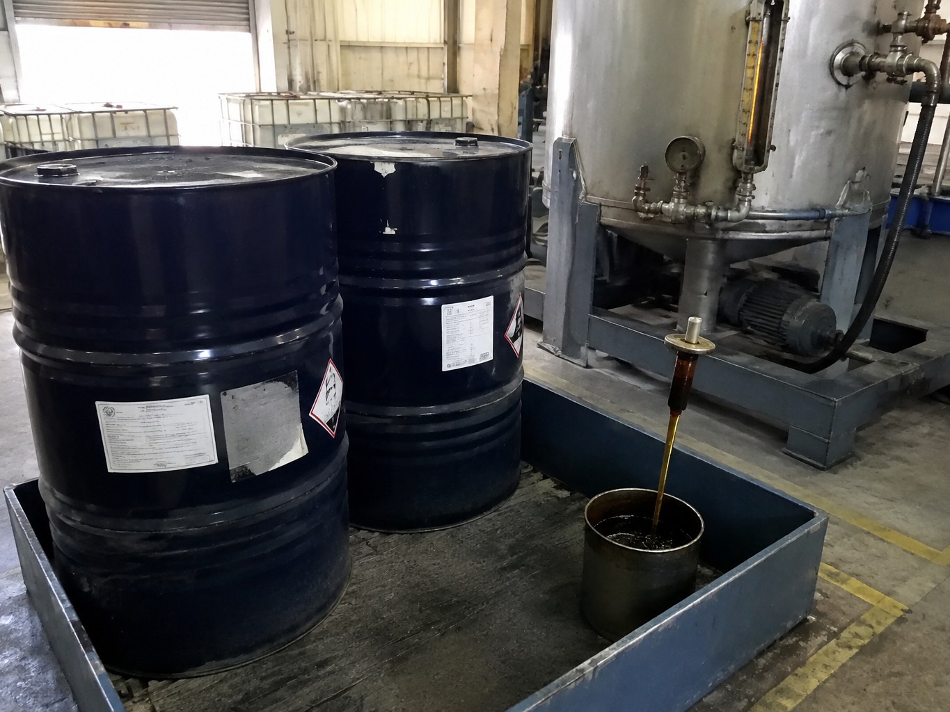 Dark octylated diphenylamine drums beside a heated lubricant additive vessel.