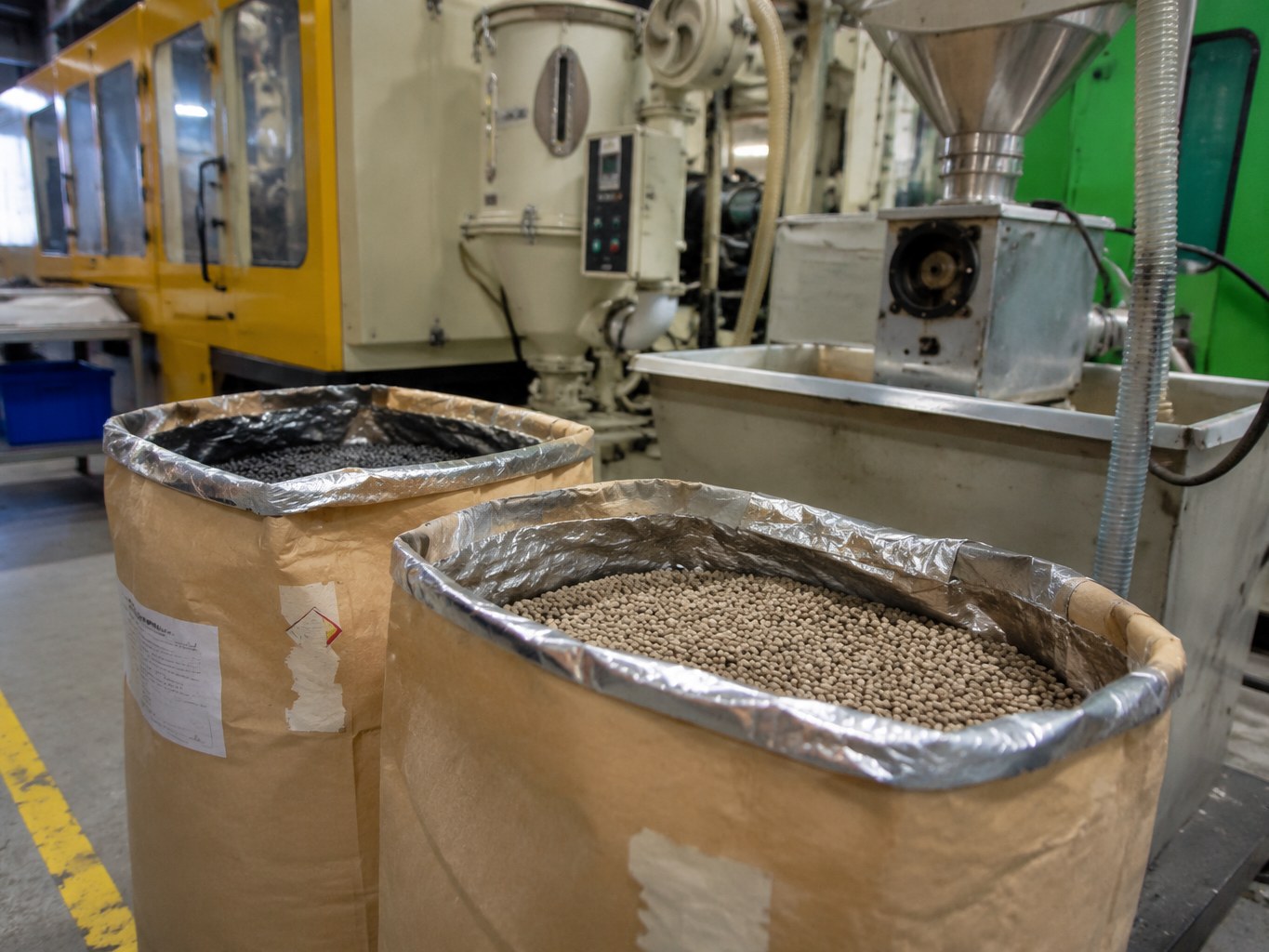 Polyphthalamide pellets in lined sacks beside a high-temperature injection moulding machine.