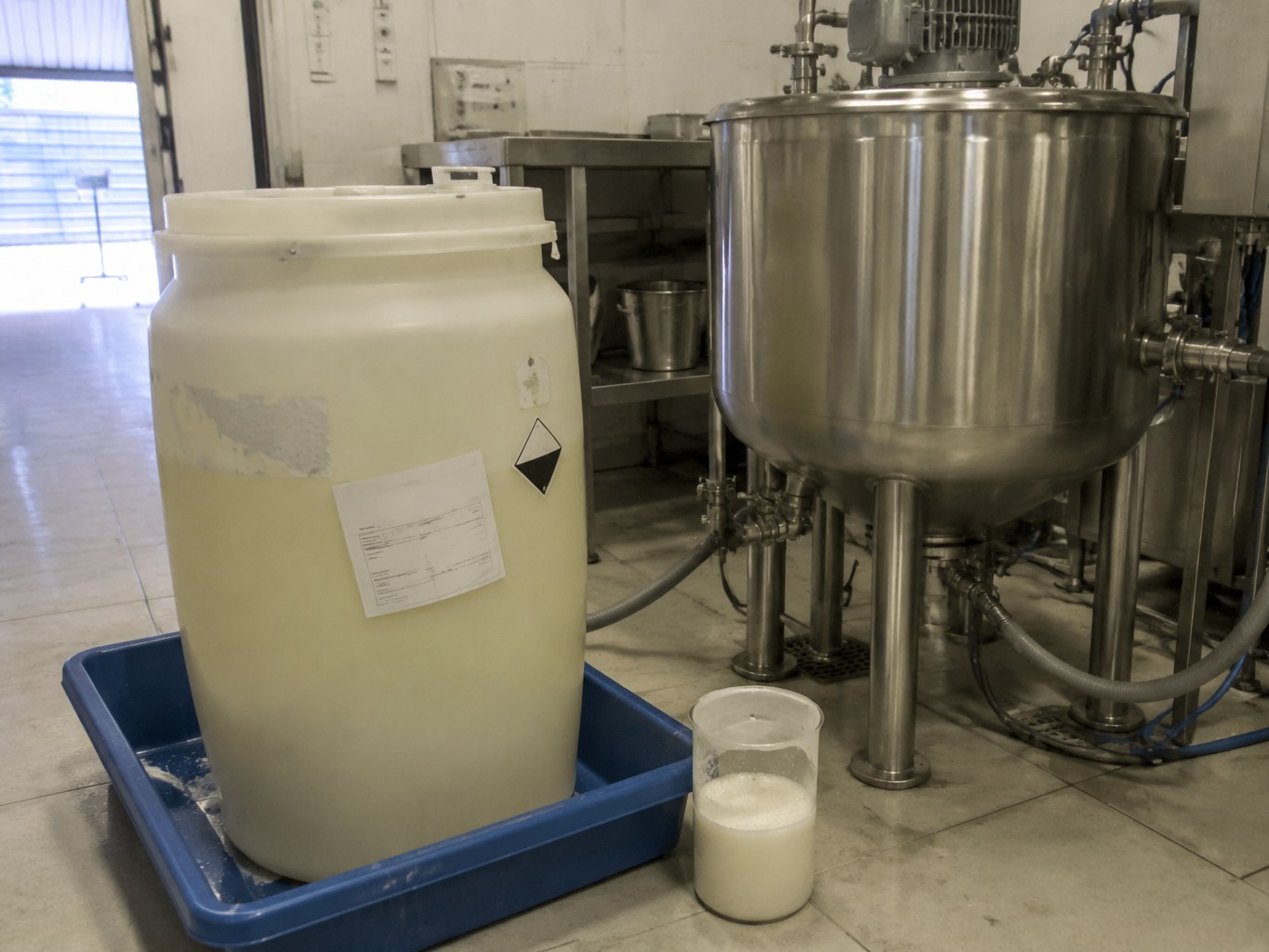 Pale potassium cocoyl glycinate liquid in an HDPE drum beside formulation vessels.