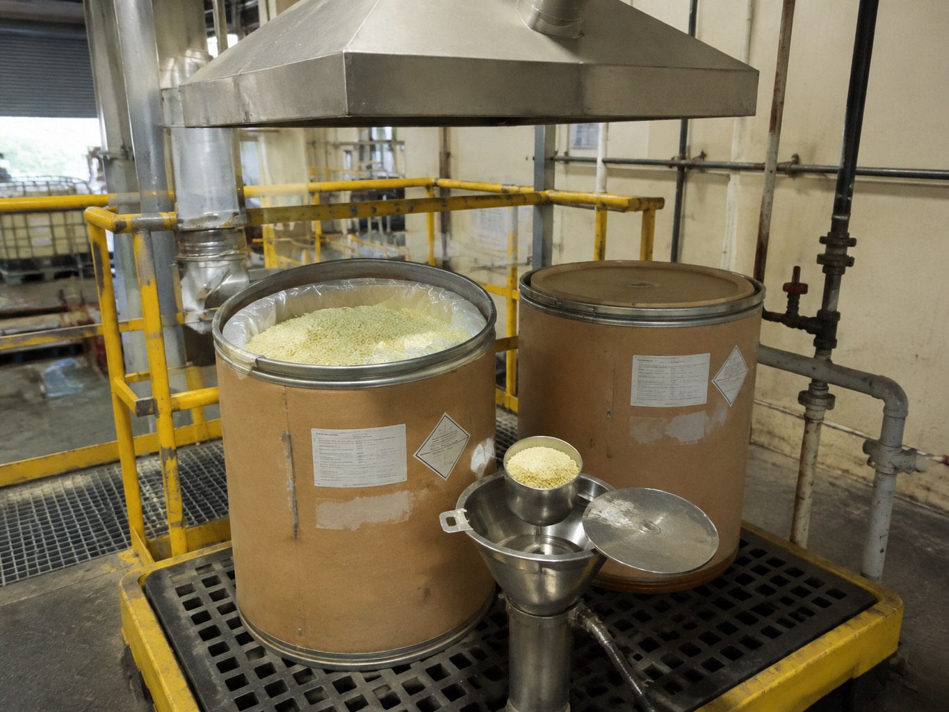 Open fibre drums of pale potassium ethyl xanthate granules beneath an extraction hood