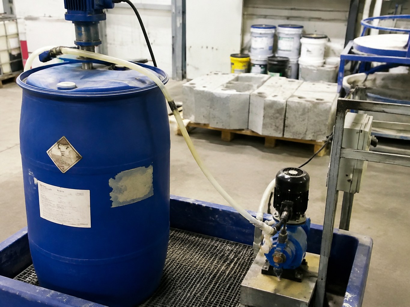 Pumped blue drum of potassium methylsilanetriolate in a masonry-additive batching area.