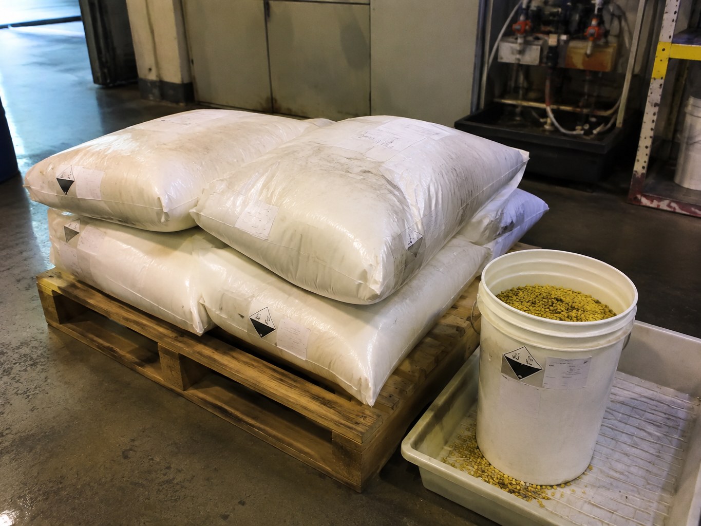 Lined sacks and sample pail of yellow-green sodium isopropyl xanthate granules.