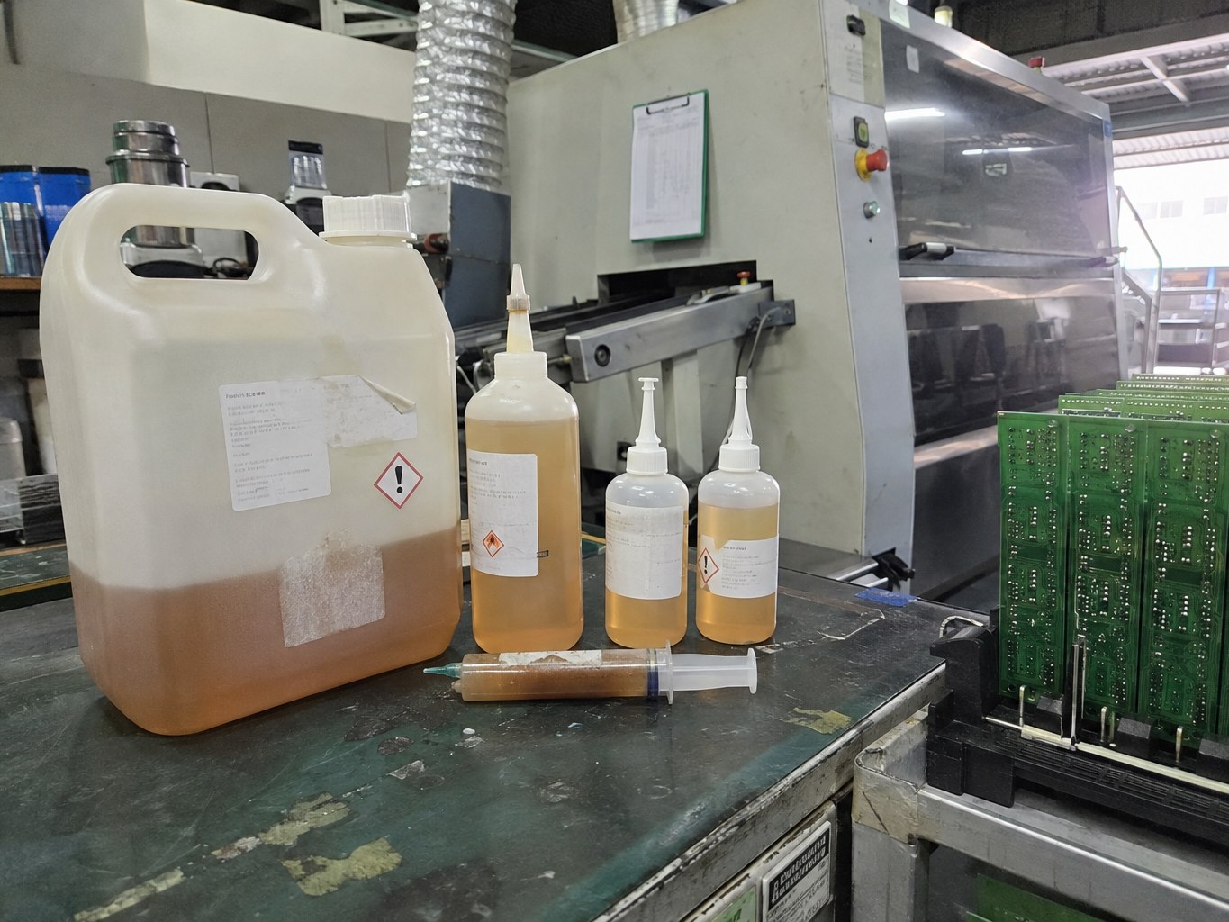 Amber solder flux in dispensing bottles beside circuit boards and soldering equipment.