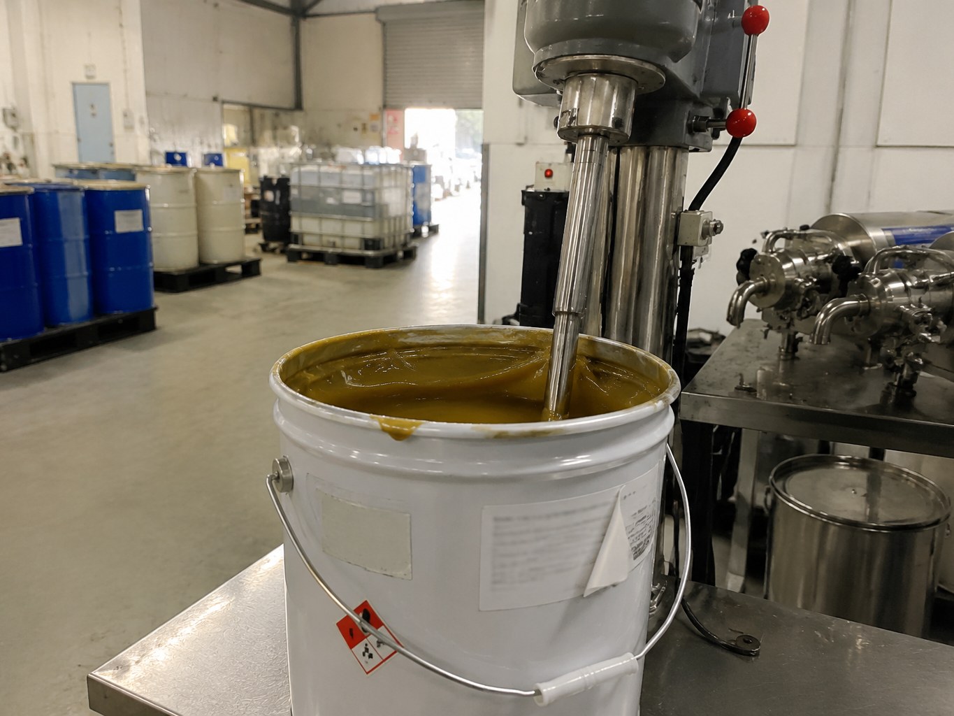 Open pail of amber sorbitan sesquioleate under a formulation mixer.