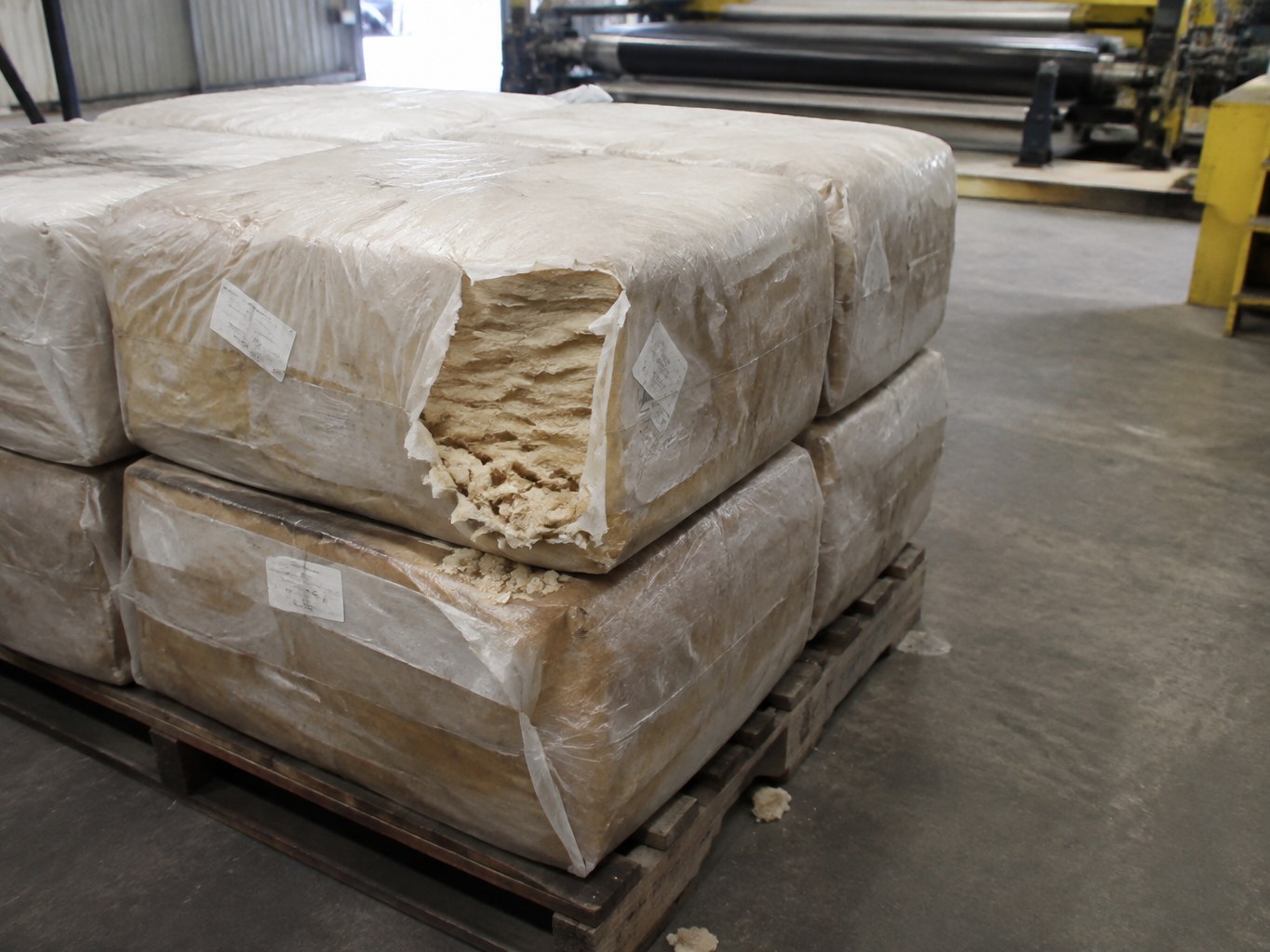Wrapped styrene-butadiene rubber bales with pale rubber exposed in a compounding warehouse.
