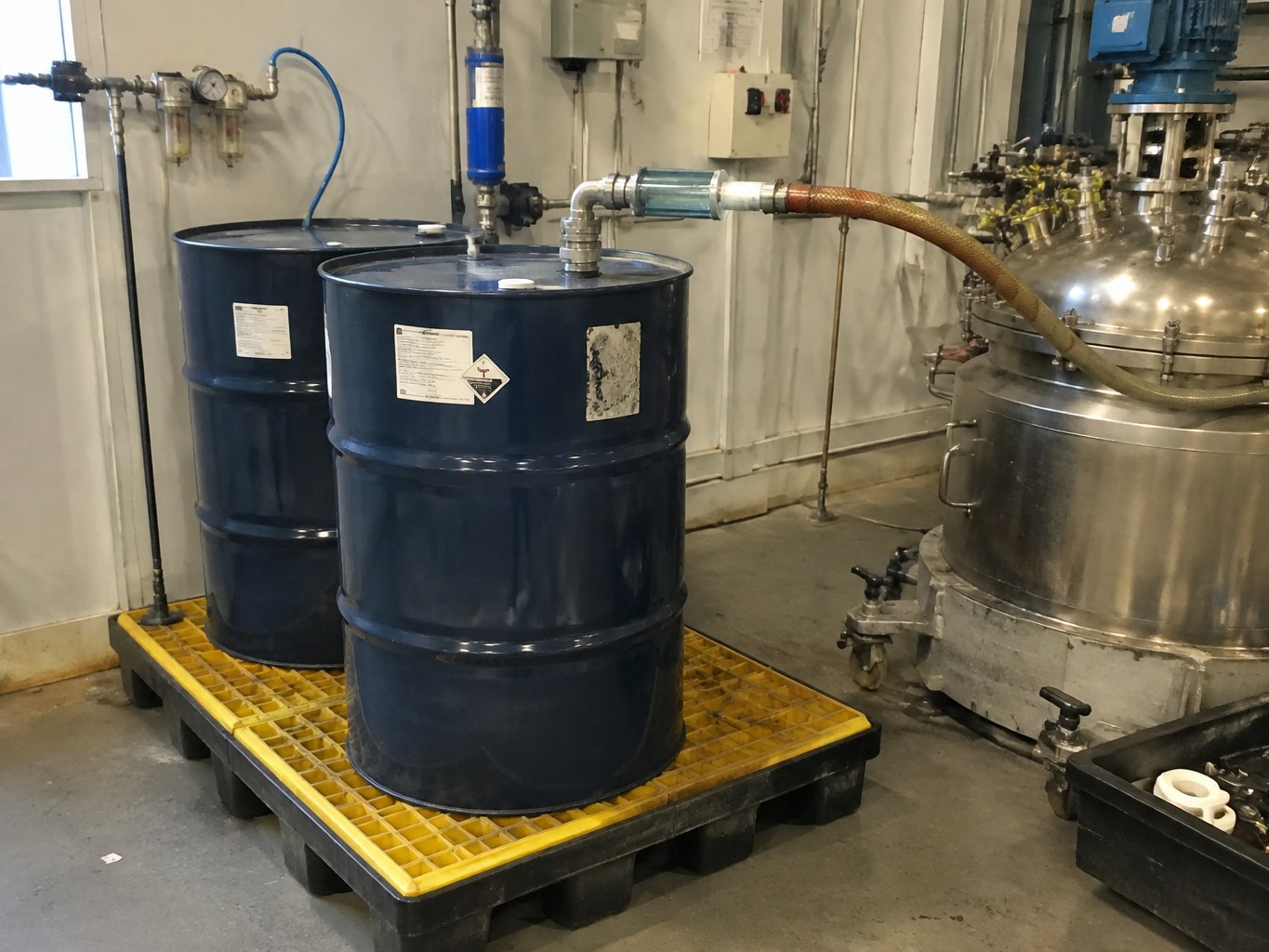 Sealed vinyltrimethoxysilane drums connected to a dry transfer line beside a reactor