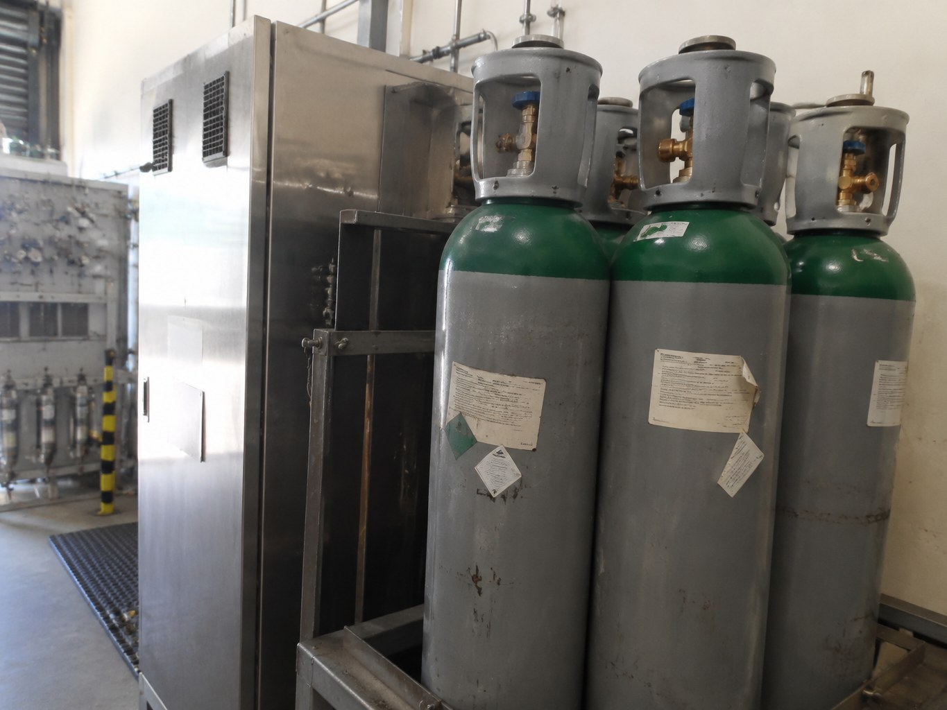 Tall xenon cylinders secured beside a specialty-gas cabinet and manifold.